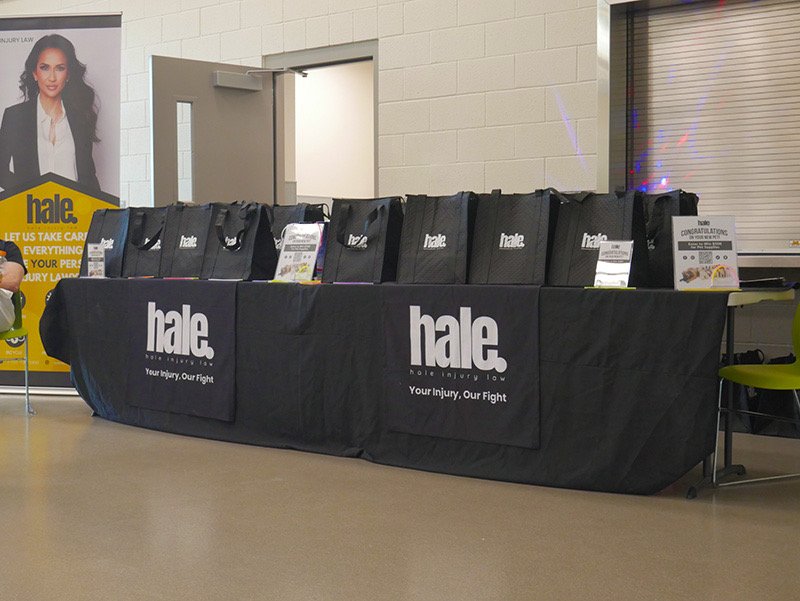 Community members gather at the Hale Injury Law booth during the Monday Night Fever pet adoptions event at The Animal Foundation, where families received swag bags and adoption fees were waived.