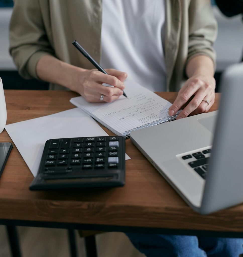 Person using a calculator at a desk while reviewing documents related to personal injury settlements.