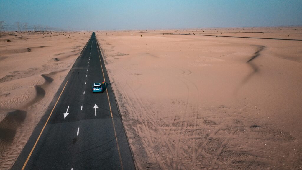 A lone vehicle driving through an isolated desert highway during the 100 deadliest days of summer driving.